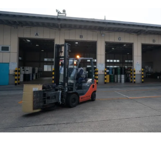 フォークリフトでドラム缶を移動している作業風景です